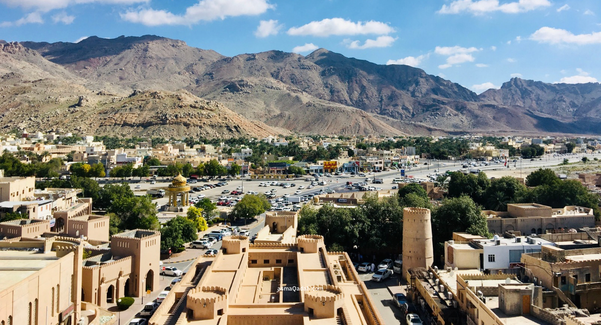منظر عام لمدينة نزوى وبرج القلعة الدائري أمام جبال الحجر في سلطنة عمان